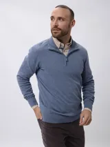 Sweater de tejido de punto en color azul, con cuello alto y cierre frontal parcial. Presenta mangas largas con puños acanalados y un pequeño detalle bordado en el pecho.