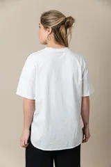 Remera blanca de algodón con cuello redondo y mangas cortas. Estampa frontal con fotografía en blanco y negro de una mujer con toalla en la cabeza y lentes de sol.