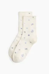Pack de cinco pares de medias de corte clásico, confeccionadas en mezcla de algodón suave. El conjunto incluye diseños en tonos neutros y pasteles, con detalles de estampado floral disperso y un par en color gris liso. Presentan un borde superior enrollado.