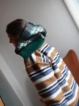 Buzo canguro oversize de paño de lana gris con capucha estampada y cuello de corderito blanco. Cuenta con aberturas laterales en el ruedo y detalles de cuero sintético marrón en el cierre frontal y etiqueta.