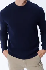 Buzo de punto con textura acanalada, color azul marino, de cuello redondo y manga larga.