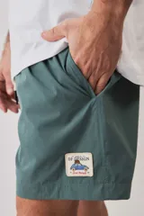 Short de baño color gris oscuro, con cintura elástica ajustable mediante cordones blancos y un pequeño parche decorativo en el borde inferior.