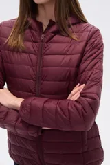 Campera acolchada tipo puffer, color beige claro, con capucha y cierre frontal. Presenta costuras horizontales y un calce entallado.