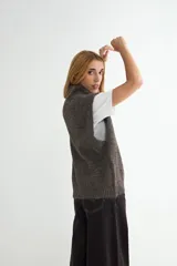 Chaleco de punto gris con cuello alto, diseño sin mangas y corte holgado.