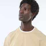 Camiseta color beige de manga corta con diseño efecto 2 en 1, presentando detalles blancos en el cuello redondo, los puños y el borde inferior.
