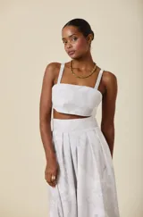 Bustier de corte estructurado con escote recto y tirantes anchos, confeccionado en tela con estampado floral sutil en tonos claros.