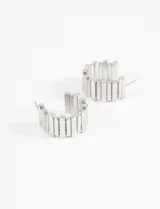 Aros plateados tipo argolla ancha, con relieve metálico tipo franjas.