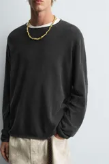 Jersey de manga larga, cuello redondo y calce relajado, color negro con efecto lavado y textura tejida.
