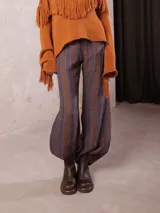 Pantalon de tiro medio con cintura elastizada, confeccionado en lino. Presenta un corte amplio tipo oxford con diseño de rayas verticales en tonos marrones y azules.