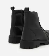 Bota de caña media color negro, estilo coturno, con cordones y cierre lateral. Suela track.