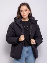 Campera puffer color beige con capucha, cierre frontal, tres bolsillos y elástico regulable en cintura y puños.