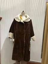 Tapado largo marrón de gamuza sintética con forro de corderito sintético en color crema. Presenta cuello, puños y bolsillos con detalle de corderito.