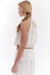 Blusa crop estilo halter con diseño abullonado en la parte inferior, confeccionada en lino con estampado de rayas verticales sutiles.