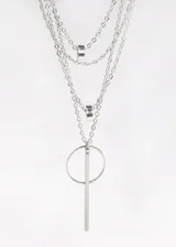Collar plateado de cuatro cadenas finas de diferentes largos, con dijes colgantes: dos dijes circulares con incrustaciones y un dije de barra vertical unida a un aro.