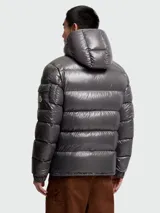 Campera corta de plumas Moncler modelo Maya, con acabado brillante, diseño acolchado horizontal, capucha integrada y cierre frontal con cremallera.