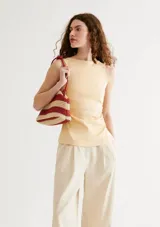 Musculosa de punto color beige con diseño sin mangas, cuello redondo y detalle de fruncido lateral.