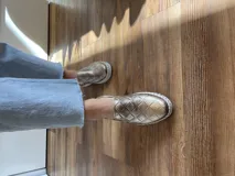 Zapatillas de cuero negro con diseño entretejido y suela blanca.