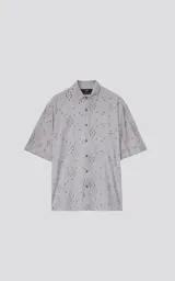 Camisa de manga corta color beige con cuello clásico y cierre de botones. Presenta un diseño de bordado calado con motivos florales y geométricos.