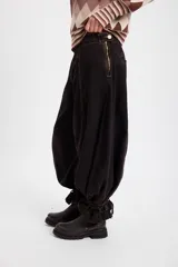 Jean de corte wide leg con efecto degradado en tonos marrón y negro. Presenta costuras verticales frontales y un diseño de puño ajustable en el bajo de la pierna.