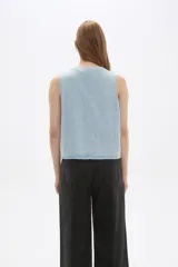 Chaleco de jean celeste con escote en V y cierre frontal con lazos.