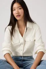 Camisa Levi's estilo western de corte estándar, color crema, con mangas largas, cuello clásico y cierre frontal con botones a presión. Presenta dos bolsillos frontales con solapa y etiqueta roja característica de la marca.