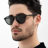 Lentes de sol INVU con montura redonda negra y lentes polarizadas grises.