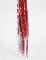 Pañuelo rectangular color rojo con lentejuelas y flecos en los extremos.