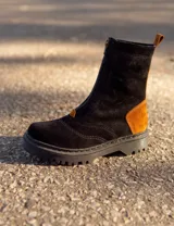 Borcego de cuero negro con detalles en marrón, suela cosida de 3 cm, forro acolchado de felpa y cierre frontal con cremallera.