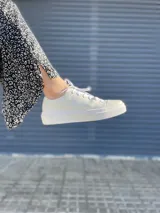 Championes blancos de cuero liso, con cordones y suela plana.