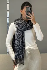 Bufanda rectangular con estampado animal print en tonos blanco y negro, con terminaciones de flecos en los extremos.