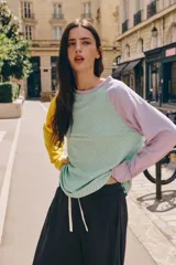 Camiseta de manga larga con diseño tricolor y patrón de rayas diagonales. Presenta cuerpo con rayas en verde y blanco, manga izquierda amarilla y manga derecha lila, con cuello redondo.