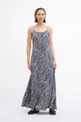 Maxi vestido de tirantes finos con estampado abstracto de líneas onduladas en tonos azul, negro y crema. Presenta un corte fluido y holgado con un ligero vuelo en el ruedo.