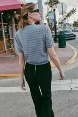 Jersey de punto con cuello redondo y manga corta, confeccionado en lana 100%. Presenta un patrón de rayas horizontales alternando azul celeste y marrón claro.