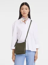 Cartera tipo crossbody de la línea Le Foulonné de Longchamp, confeccionada en cuero con textura granulada. Presenta un diseño rectangular compacto con solapa, correa larga ajustable para llevar al hombro o cruzada y logo de la marca grabado discretamente en el frente.