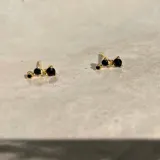 Par de aros dorados con tres piedras negras en forma ascendente.