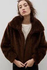 Campera corta de piel sintética en color crema, con cuello amplio tipo solapa y cierre frontal.