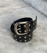 Cinturón de cuero vacuno color marrón con tachas metálicas plateadas.