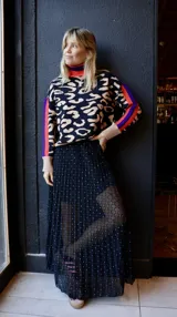 Sweater de punto con estampado animal print, cuello alto tipo polera en combinación de colores rosa y bordó, y detalles de franjas laterales en las mangas.