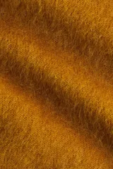 Buzo oversized de punto suave en color mostaza, confeccionado en mezcla de lana y mohair. Presenta un diseño de hombros caídos con cuello redondo, puños y bajo acanalados.