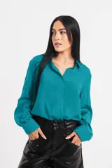 Camisa de satén color turquesa, con cuello clásico, cierre frontal de botones y mangas largas con puños anchos.