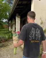 Remera marrón oversize de manga corta con estampado gráfico en la espalda de dos gatos de estilo retro con cuchillos y texto "Kahoa Industries".