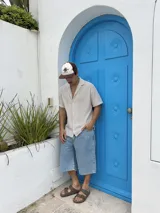 Camisa tejida a rayas verticales color beige y blanco, de corte recto, manga corta y cuello cubano.