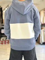 Hoodie de felpa con capucha y medio cierre frontal, diseño en bloques de color celeste y blanco, con bordados decorativos en el pecho.