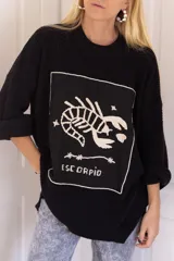Sweater negro de tejido de punto con cuello redondo y mangas largas. Presenta un diseño bordado en el frente con el signo zodiacal Escorpio.
