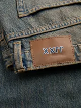 Jean de denim para mujer, de tiro bajo y corte loose fit con pernera amplia. Presenta un lavado con efecto desgastado de tono amarillento, cierre frontal con botón y cinco bolsillos clásicos.