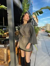 Blusa verde con mangas anchas, corte holgado y cinturón dorado con hebilla cuadrada.