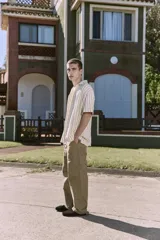 Camisa de manga corta a rayas verticales color crudo y verde, con cuello resort, corte holgado y cierre frontal con botones.