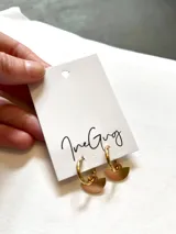 Aros colgantes con argolla dorada y dije semicircular color cobre.