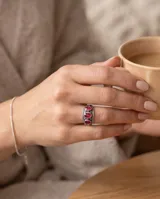 Anillo de plata envejecida con tres piedras naturales de rubí en corte ovalado en disposición vertical, con detalles grabados en el metal.
