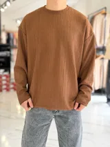 Buzo oversize marrón de manga larga, confeccionado en tela texturada con líneas verticales, cuello redondo y calce holgado.